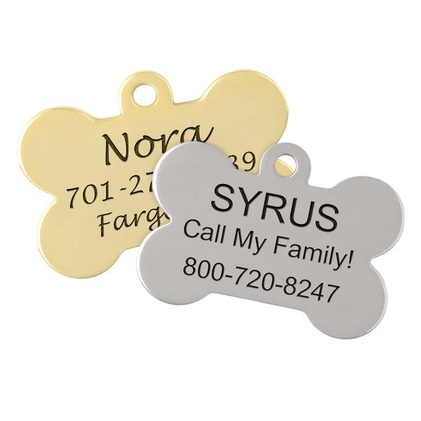 two dog tags, one in gold and one in silver, both with the name "Nora" and the phone number "701-2789" printed on them.