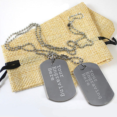 two gray metal tags with personalized text, placed on a burlap bag.